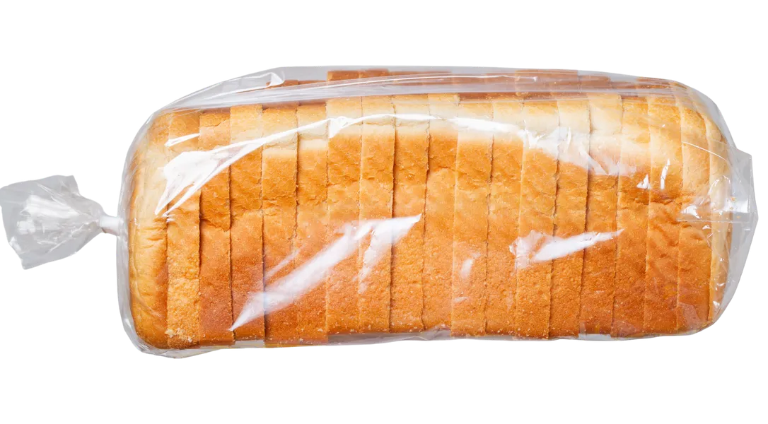 A sliced loaf of bread in a clear bread bag with a twist tie