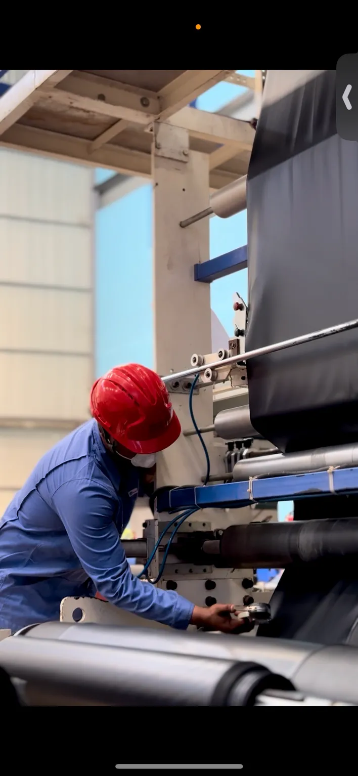 Mr. Plastic operator in a red hard hat adjusting a film extrusion line