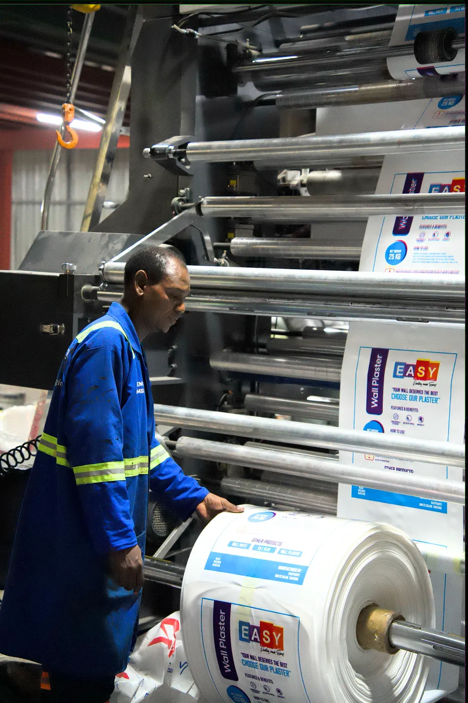 Operator feeding a roll of printed packaging film through a Mr. Plastic flexo press