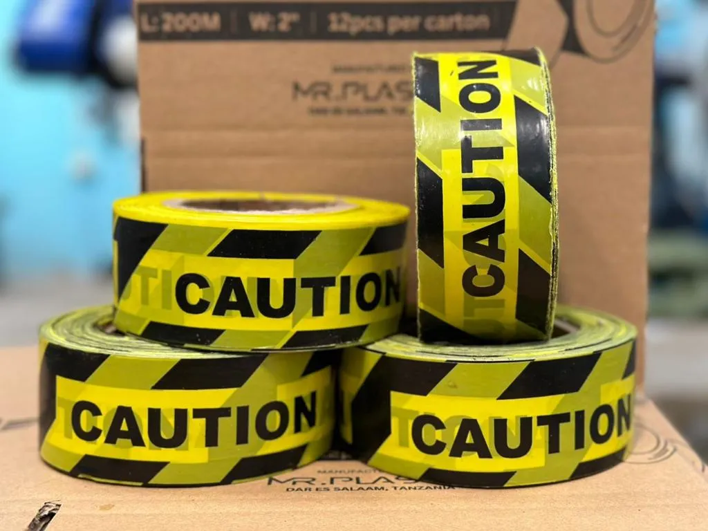 Commando caution tape rolls in yellow and black in front of a Mr. Plastic carton