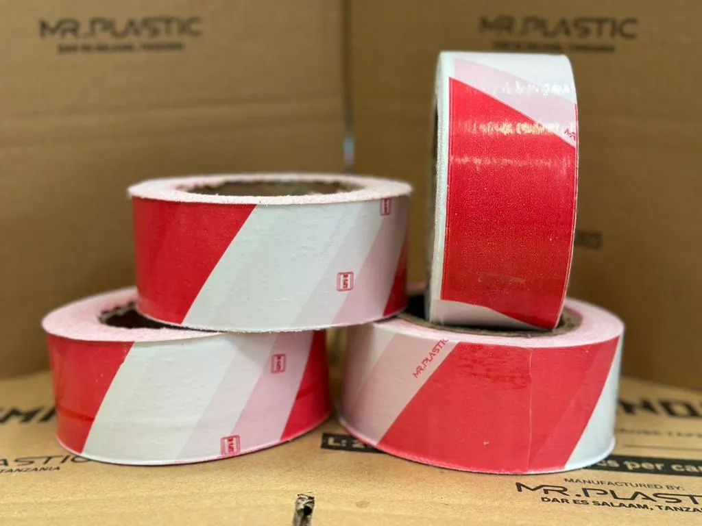 Red and white Commando warning tape rolls stacked on Mr. Plastic cartons