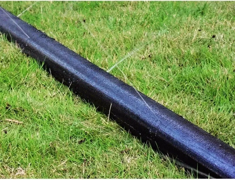 Black irrigation tubing laid along a grass field